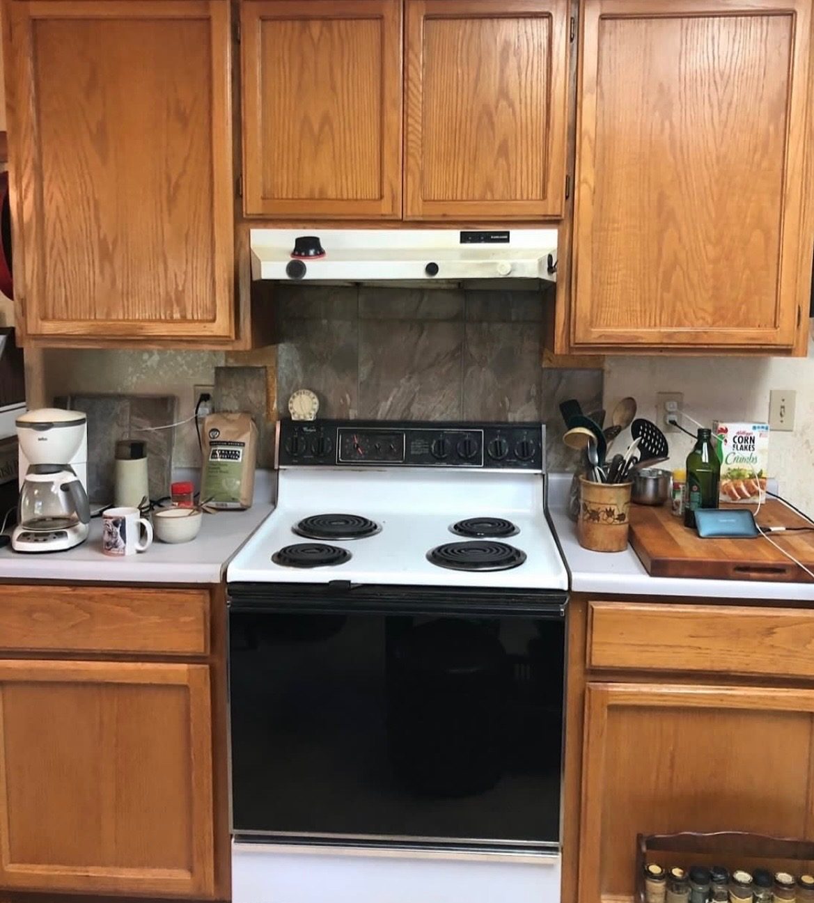 The same kitchen before: dated oak cabinets and worn backsplash