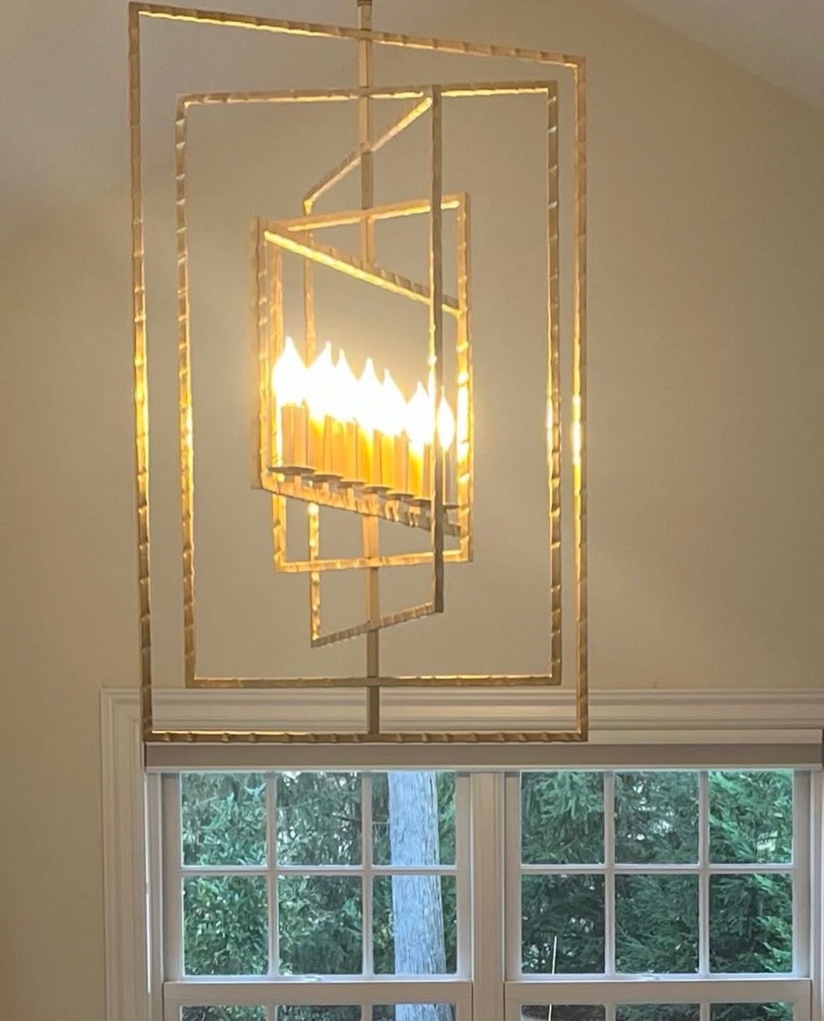 Sculptural gold chandelier above a paned window