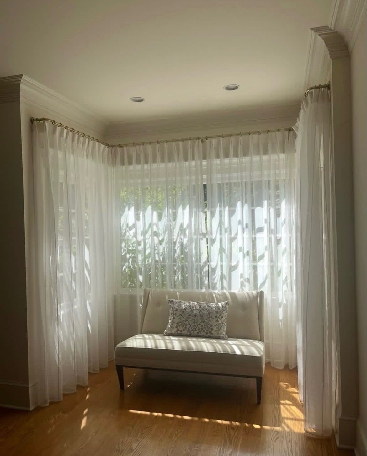 Corner window seat wrapped in custom sheer drapery
