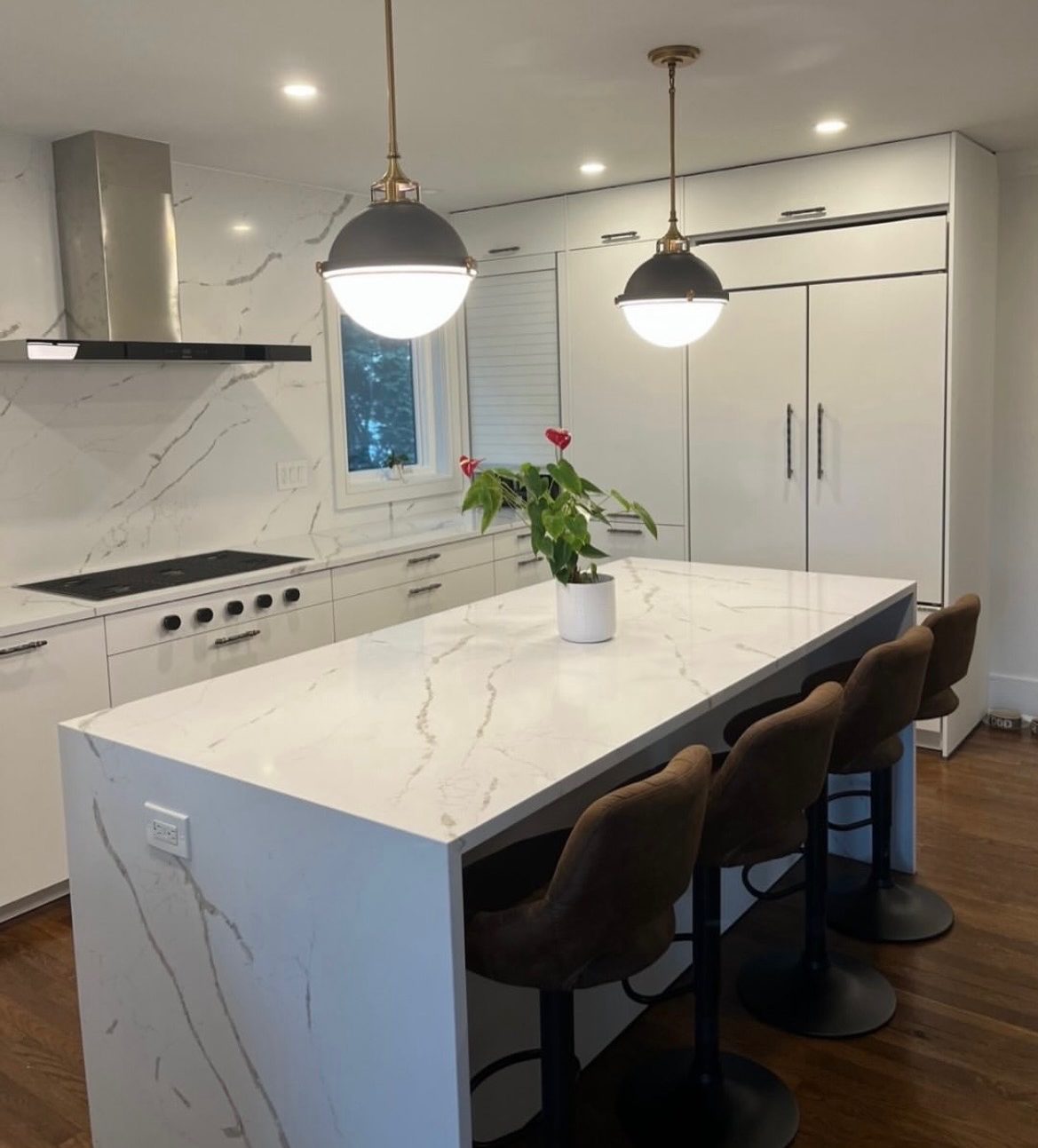 Quartz island with built-in wall ovens and leather counter stools