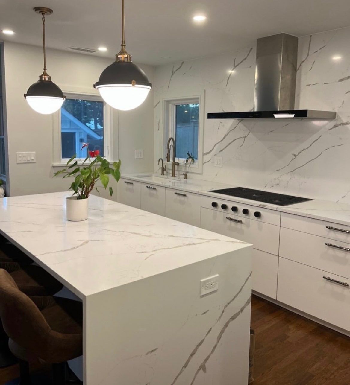 White kitchen with quartz waterfall island and brass pendant lighting